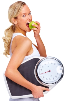 Young woman eating apple and carrying a weight scale over white background